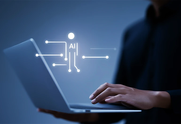 Eine Hand an einem Laptop. Davor der Schriftzug AI